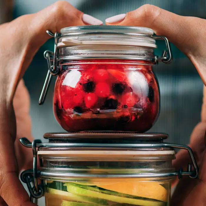 desserts-bocaux-fruits-rouges-citron-fous-du-bocal-ambares Deux bocaux de desserts maison aux fruits rouges et citron tenus par un client du restaurant Les Fous du Bocal à Ambarès-et-Lagrave