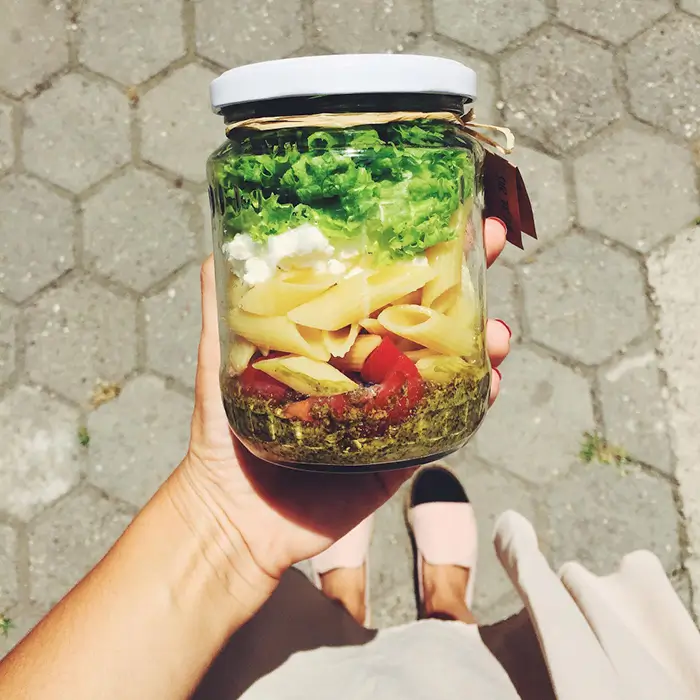 bocal-pates-pesto-emporter-street-food-ambares-et-lagrave Client tenant un bocal de pâtes au pesto avec légumes à emporter, concept street food écologique du restaurant Les Fous du Bocal